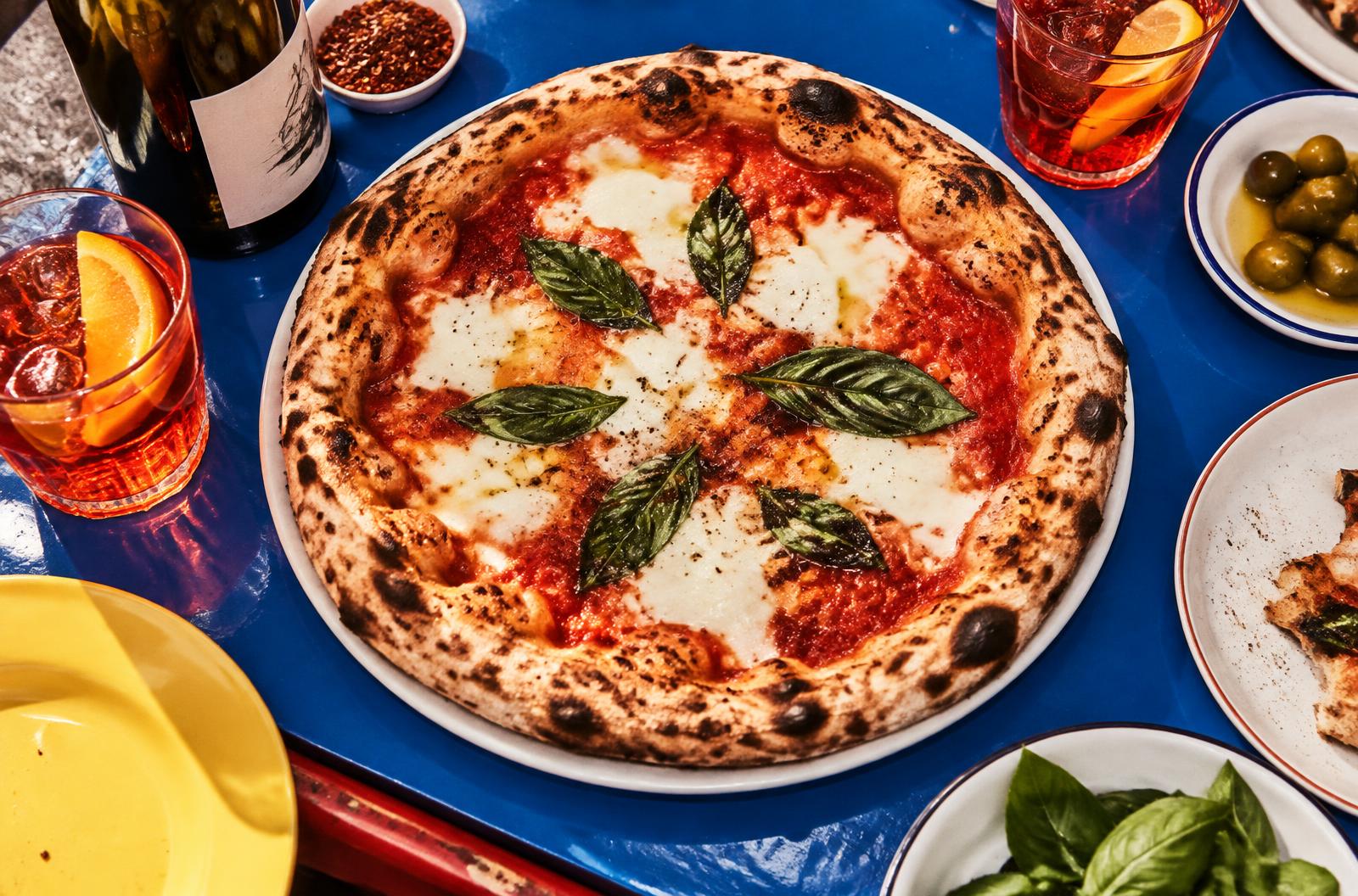Neapolitanische Pizza Margherita mit Aperitivo auf blauem Tisch